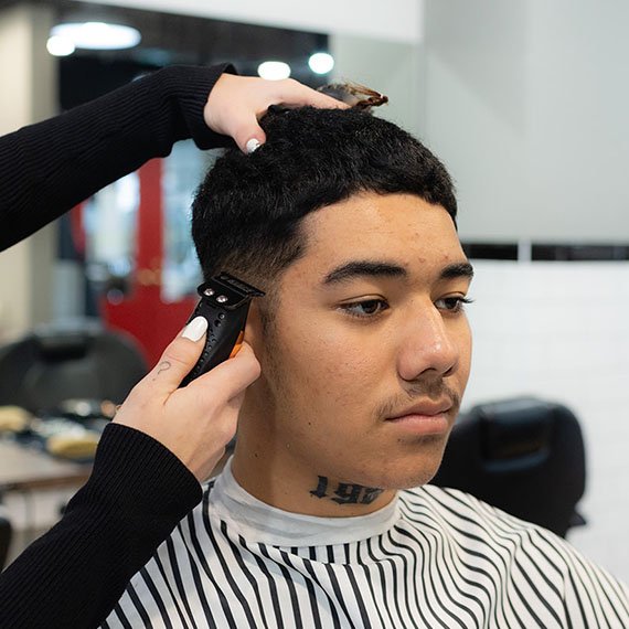 Photo of a young man getting his hair cut.